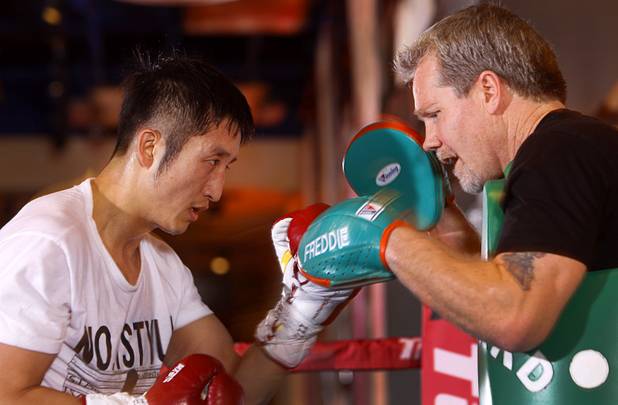 Chinese light flyweight boxer Zou Shiming (L) works on his timing with trainer Freddie Roach during a workout in a training facility at the Palazzo in Las Vegas, Nevada February 8, 2013. Zou, a two-time Olympic gold medalist and three-time world amateur champion, will make his professional debut April 6 at the Venetian Macao Resort in Macau.
