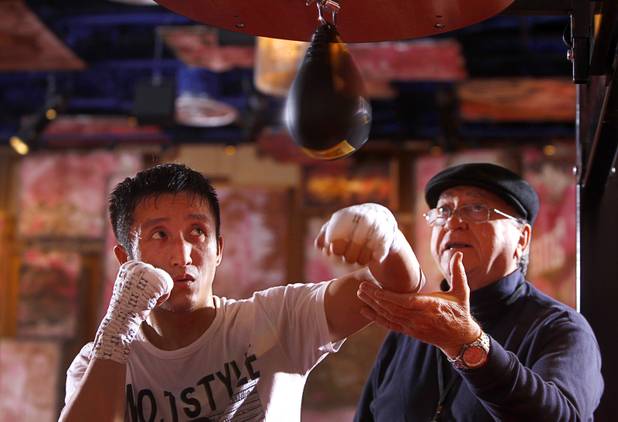 Chinese light flyweight boxer Zou Shiming (L) gets advice from assistant Miguel Diaz as he hits a speed bag during a workout in a training facility at the Palazzo in Las Vegas, Nevada February 8, 2013. Zou, a two-time Olympic gold medalist and three-time world amateur champion, will make his professional debut April 6 at the Venetian Macao Resort in Macau.