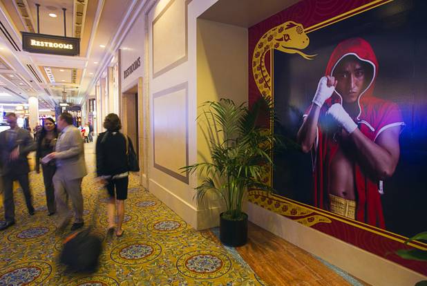 Casino patrons pass by a training facility with the image of Chinese light flyweight boxer Zou Shiming at the Palazzo in Las Vegas, Nevada February 8, 2013. Zou, a two-time Olympic gold medalist and three-time world amateur champion, is training in Las Vegas ahead of his professional debut April 6 at the Venetian Macao Resort in Macau.