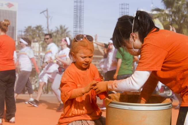 Makenzie, left, covered in orange powder, helps volunteers fill up bottles at the 5K Color Run, Saturday, Feb. 16, 2013. 
