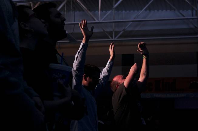 Grace City Church members are spotlit in the dimly lit room as they raise their arms during the song session of the church's Sunday service, Feb. 17, 2013. The new Las Vegas church rents out the Jack Schofield Middle School auditorium as a temporary venue to hold their Sunday service.