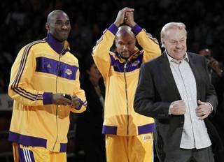 In this Oct. 26, 2010 file photo, Los Angeles Laker owner Jerry Buss, right, walks out onto the court during the NBA championship ring ceremony as Kobe Bryant, left, and Derek Fisher look on before a basketball game against the Houston Rockets in Los Angeles. 