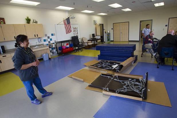 Specialized teacher's assistant Susana Price looks over a wheelchair swing that is being assembled in a physical education room at the new John F. Miller School, a school which serves students with disabilities and special needs, Wednesday Feb. 20, 2013. The school has been nominated for a national design award.