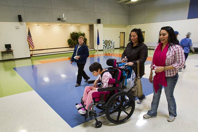 Student Claudia Aceves heads to a classroom with her mother Rafael, center, and specialized teacher's assistant Angelica Mojica after getting cake in a multipurpose room following an official opening ceremony at the new John F. Miller School, a school which serves students with disabilities and special needs, Wednesday Feb. 20, 2013. The school has been nominated for a national design award.