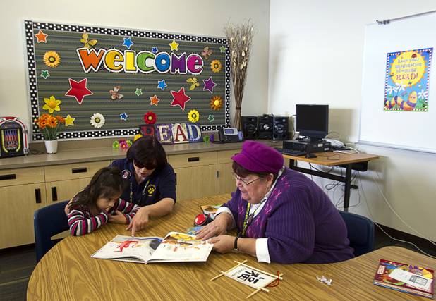 Librarian Sandy Feink reads to student Sindian Guerro, 6, in the library at the new John F. Miller School, a school which serves students with disabilities and special needs, Wednesday Feb. 20, 2013. Specialized teacher's assistant Susan Farrar is at center. The school has been nominated for a national design award.