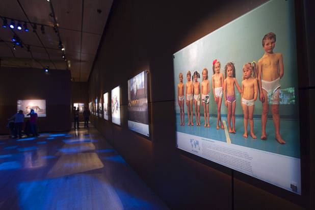 Visitors look over photos at the 50 Greatest Photographs of National Geographic, an exhibit of National Geographics most iconic photos, at the Imagine Exhibitions Gallery in the Venetian Wednesday Feb. 20, 2013. The photo at right shows Moscow schoolchildren in a photo taken by photographer Gerd Ludwig in 1993.