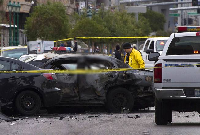 A crime scene analyst walks by a burned-out car after a shooting and multi-car accident that left three people dead and three injured on the Las Vegas Strip early Thursday morning Feb. 21, 2013. EDITOR’S NOTE: This photo has been digitally altered to obscure an image of one of the victims.

