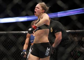 Ronda Rousey celebrates defeating Liz Carmouche after their UFC 157 women's bantamweight championship mixed martial arts match in Anaheim, Calif., Saturday, Feb. 23, 2013. Rousey won the first womens bout in UFC history, forcing Carmouche to tap out in the first round. (AP Photo/Jae C. Hong)