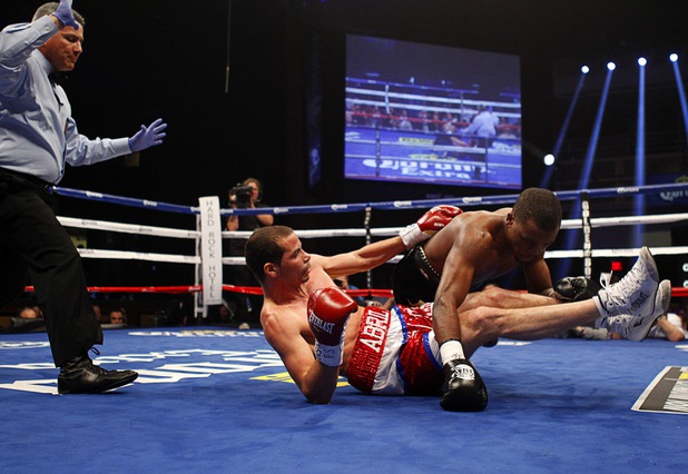 WBA lightweight champion Richard Abril (L) of Cuba and Sharif Bogere of Uganda fall to the canvas during their title at the Hard Rock Hotel in Las Vegas, Nevada March 2, 2013. Abril retained his title with a unanimous decision victory. Referee Russell Mora steps in at left.
