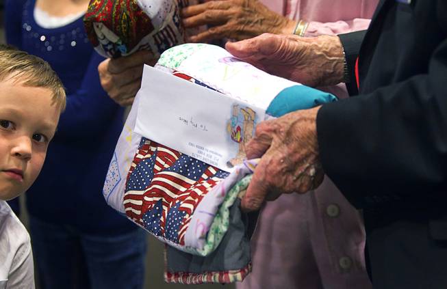 World War II veterans hold quilts as they are honored during Veterans Court in Henderson Thursday, March 7, 2013. Holden Miller, 5, helped to hand out the quilts. Moms Love Quilts, a local group that gives out quilts to military members, provided the quilts.