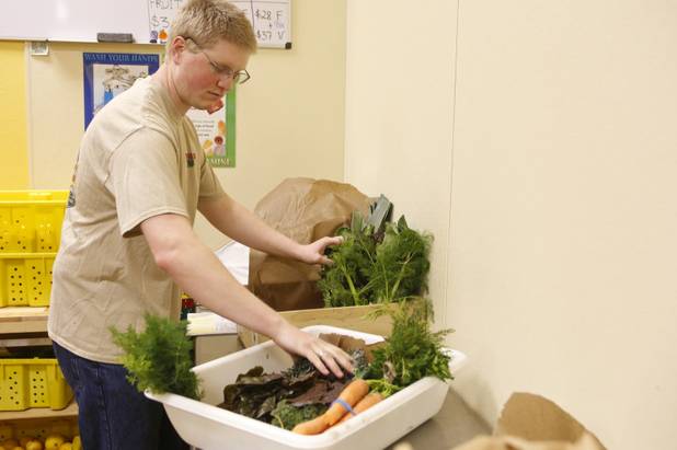 Wes Zarnowitz packs a wooden crate with fresh fruit and vegetables for a customer at Trish & Ed's Organics, Wednesday, March 6, 2013.
