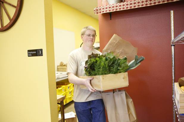 Wes Zarnowitz carries a wooden crate with fresh fruit and vegetables at Trish & Ed's Organics, Wednesday, March 6, 2013.