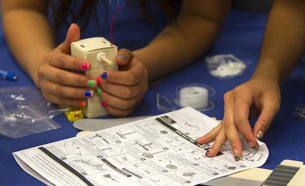 A student reads instructions as her team builds a robot during the annual HerWorld workshop at the Henderson Convention Center Thursday, March 14, 2013. About 230 students attended the workshop, sponsored by DeVry University, intended to introduce female high school students to careers in science, technology, engineering and math.