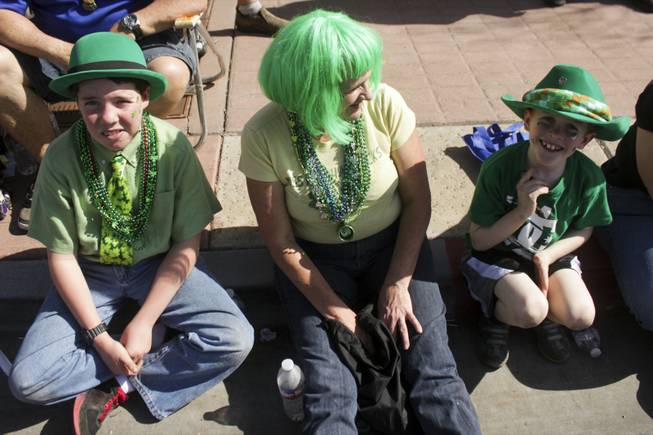 Parade goers sit on the sidewalk during the St. Patrick's Day Parade in downtown Henderson, Saturday, Mar. 16, 2013.