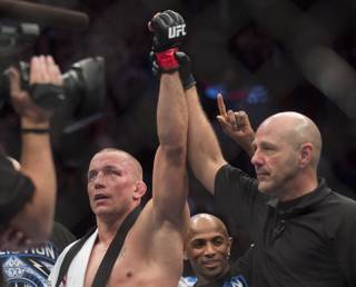 Georges St-Pierre from Canada, left, has his arm raised by an official after defeating Nick Diaz from the United States in their UFC 158 mixed martial arts title fight in Montreal, Saturday, March 16, 2013. (AP Photo/The Canadian Press, Graham Hughes)
