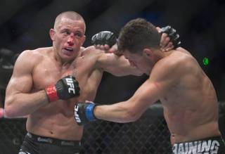 Georges St-Pierre, left, from Canada lands a blow to Nick Diaz from the United States  during their UFC 158 welterweight mixed martial arts title fight in Montreal, Saturday, March 16, 2013. (AP Photo/The Canadian Press, Graham Hughes)