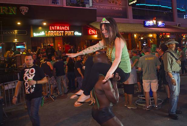 Ty Cardwell of Dallas tries to lift up Megan Oesterling of Las Vegas outside Hennessey's Tavern on Fremont Street during St. Patrick's Day Sunday, March 17, 2013.