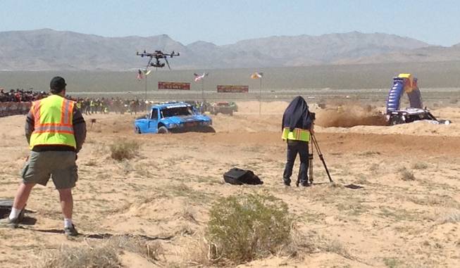 A crew uses cameras mounted on a tripod and an aerial drone to capture action from the Mint 400 off-road race Saturday, March 23, 2013, near Las Vegas.