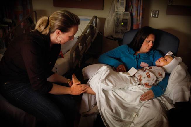 Staci Freeman, left, and her sister, Jami Valentine, try to comfort Arefa after the girl had skin graft surgery in July at Shriner’s Hospital in Los Angeles.