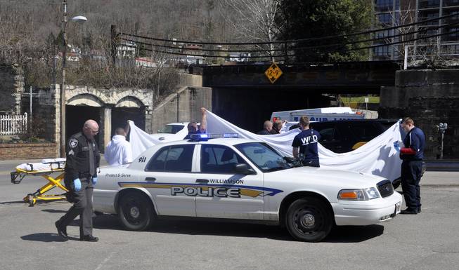 Law enforcement officers and emergency service personnel cover the vehicle at the scene of the shooting in downtown Williamson, W.Va., Wednesday, April 3, 2013, where Sheriff Eugene Crum was shot and killed at point blank range.