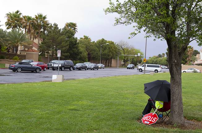 Crossing guard Lois Kern waits for schoolchildren under an umbrella at Mountain View Park in Henderson, April 8, 2013. The National Weather Service reported that high winds and showers are expected later this week.