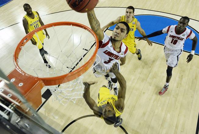 Louisville guard Peyton Siva (3) shoots against a Michigan defense during the first half of the NCAA Final Four tournament college basketball championship game Monday, April 8, 2013, in Atlanta. 