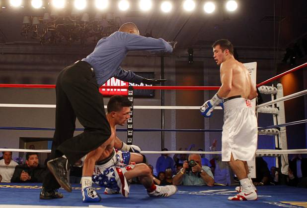 Referee Kenny Bayless stops the fight after Bahodir "Baha" Mamadjonov, right, of Uzbekistan knocks down Angelo "La Cobra" Santana of Cuba during a WBA lightweight bout at the Treasure Island Friday, April 12, 2013.