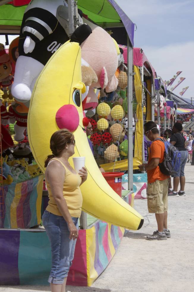 A women stands next to a giant stuffed banana being offered as a prize at one of the carnival game stands at the 2013 Clark County Fair, Saturday, April 13, 2013.