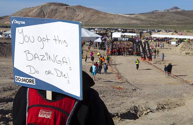 A woman carries a sign to encourage her husband during the Tough Mudder in Beatty, Nev. Sunday, April 14, 2013. Tough Mudder events are hardcore 10-12 mile obstacle courses designed to test all-around strength, stamina, mental grit, and camaraderie.
