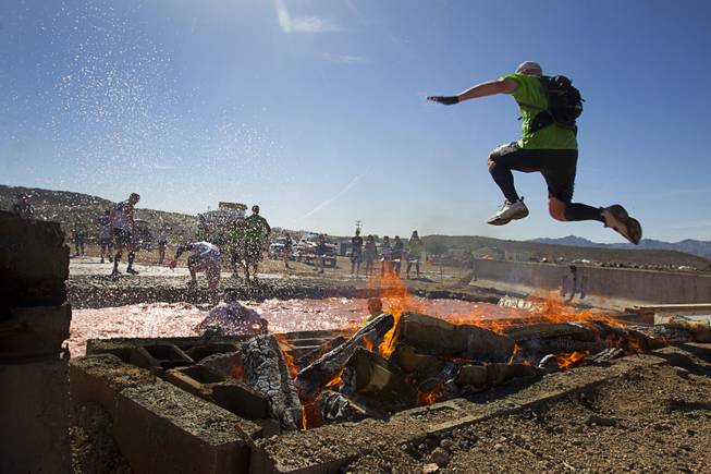 A man leaps over fire into a water pit during the Tough Mudder in Beatty, Nev. Sunday, April 14, 2013. Tough Mudder events are hardcore 10-12 mile obstacle courses designed to test all-around strength, stamina, mental grit, and camaraderie.
