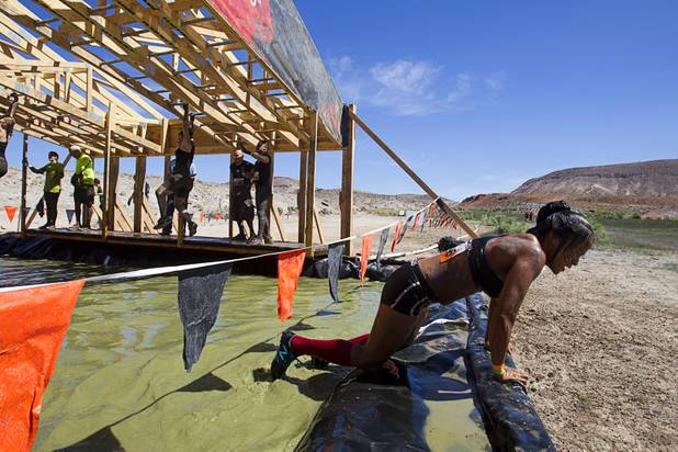 A woman pulls herself out of the water after falling from the "Funky Monkey" obstacle during the Tough Mudder in Beatty, Nev. Sunday, April 14, 2013. Tough Mudder events are hardcore 10-12 mile obstacle courses designed to test all-around strength, stamina, mental grit, and camaraderie.