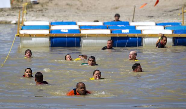 Competitors swim under barrels during the Tough Mudder in Beatty, Nev. Sunday, April 14, 2013. Tough Mudder events are hardcore 10-12 mile obstacle courses designed to test all-around strength, stamina, mental grit, and camaraderie.