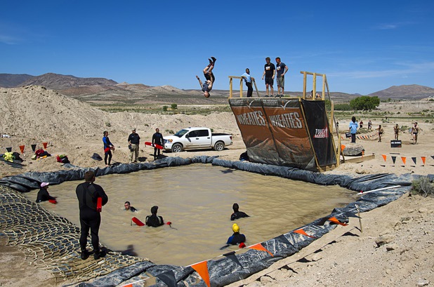A man does a flip off the "Walk the Plank" obstacle during the Tough Mudder in Beatty, Nev. Sunday, April 14, 2013. Tough Mudder events are hardcore 10-12 mile obstacle courses designed to test all-around strength, stamina, mental grit, and camaraderie.