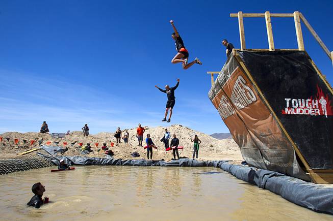Competitors jump from the "Walk the Plank" obstacle during the Tough Mudder in Beatty, Nev. Sunday, April 14, 2013. Tough Mudder events are hardcore 10-12 mile obstacle courses designed to test all-around strength, stamina, mental grit, and camaraderie.