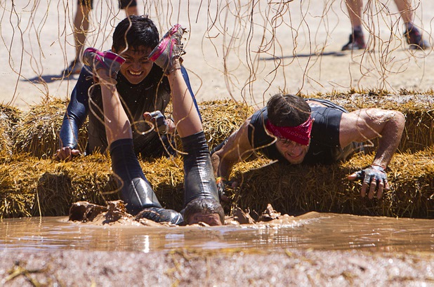 Rebecca Rajkowski, center, falls after being shocked by live wires in the "Electroshock Therapy" obstacle during the Tough Mudder in Beatty, Nev. Sunday, April 14, 2013. Tough Mudder events are hardcore 10-12 mile obstacle courses designed to test all-around strength, stamina, mental grit, and camaraderie.