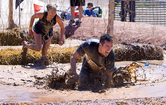Kimberly Pettit and James Russell of Las Vegas make their way though the "Electroshock Therapy" obstacle during the Tough Mudder in Beatty, Nev. Sunday, April 14, 2013. Tough Mudder events are hardcore 10-12 mile obstacle courses designed to test all-around strength, stamina, mental grit, and camaraderie.