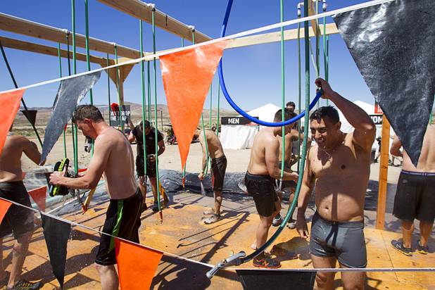 Competitors rinse off in an outdoor shower after finishing the Tough Mudder in Beatty, Nev. Sunday, April 14, 2013. Tough Mudder events are hardcore 10-12 mile obstacle courses designed to test all-around strength, stamina, mental grit, and camaraderie.