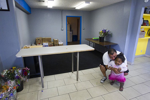 Volunteer Rick Mora plays with Jazzy, 2, the daughter of another volunteer, at Casa de Luz, a small church in the Naked City area Monday, April 15, 2013. The church, which currently services about 1,800 area residents with a food pantry, is beginning on a major renovation project.