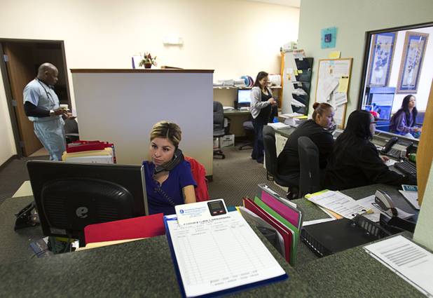 Lupe Miron, foreground on the phone, reschedules a patient's appointment at the Advanced Urgent Care clinic, 9975 S. Eastern Ave., Monday, April 15, 2013.