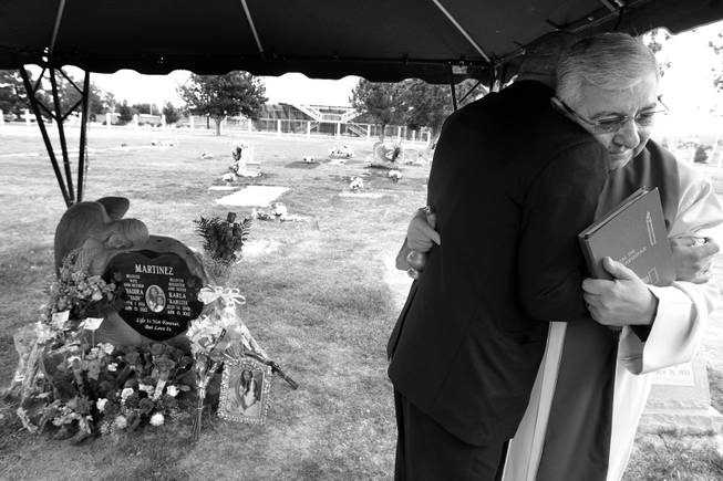 The Rev. Julio Alberto Alzate hugs Arturo Martinez-Sanchez after blessing the headstone at the gravesite of Yadira and Karla Martinez on April 16, 2013, at Woodlawn Cemetery in Las Vegas.