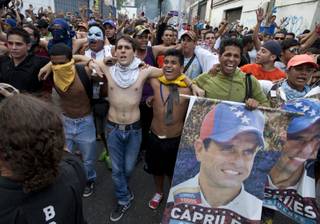 Demonstrators, one holding a poster of opposition presidential candidate Henrique Capriles, shout slogans against the government and the official election results in the Altamira neighborhood in Caracas, Venezuela, Monday, April 15, 2013. 