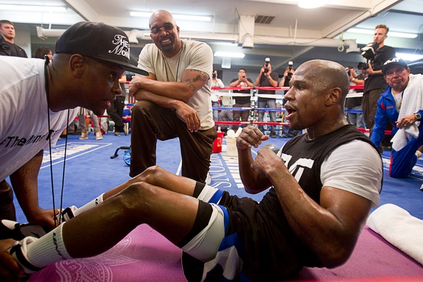 DeJuan Blake (L) helps boxer Floyd Mayweather Jr. with sit-ups as Leonard Ellerbe (C), CEO of Mayweahter Promotions, looks on at the Mayweather Boxing Club Wednesday, April 17, 2013. Mayweather will defend his WBC welterweight title against Robert Guerrero at the MGM Grand Garden Arena on May 4.