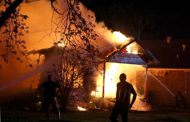 A person looks on as emergency workers fight a house fire after a near by fertilizer plant exploded Wednesday, April 17, 2013, in West, Texas.