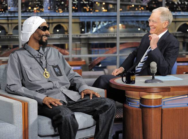 In this photo provided by CBS, rapper/actor Snoop Lion, formerly Snoop Dogg, left, talks with host David Letterman on the set of the Late Show with David Letterman, Thursday, April 25, 2103 in New York. 