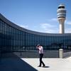 The control tower stands in the background as a passenger paces while on the phone outside the international terminal at Hartsfield-Jackson airport, Friday, April 26, 2013, in Atlanta. Congress easily approved legislation ending furloughs of air traffic controllers that have delayed hundreds of flights daily, infuriating travelers and causing political headaches for lawmakers.