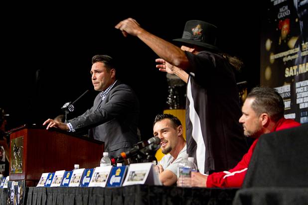 Oscar De La Hoya, left, president of Golden Boy Promotions, stands at the podium as Ruben Guerrero (standing right), father of boxer Robert Guerrero, continues to trash talk Floyd Mayweather Jr. during a news conference at the MGM Grand Wednesday, May 1, 2013.