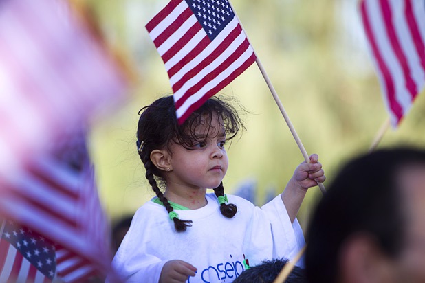 Juliana Martinez, 3, waves a flag while riding on her father's shoulders during a May Day rally and march for comprehensive immigration reform at the George Federal Building Wednesday, May 1, 2013. The event started at the courthouse, then marchers traveled south on Las Vegas Boulevard, finishing with a rally at St. Louis Square near the Stratosphere.