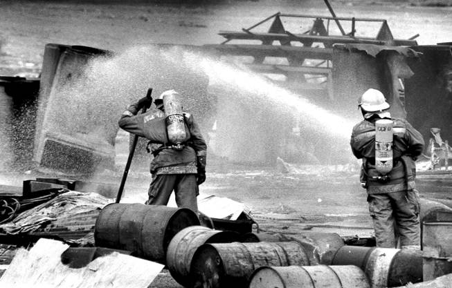 Firefighters spray water on twisted metal to keep fire and fumes from escaping at the Pacific Engineering Production Company of Nevada plant May 5, 1988. 