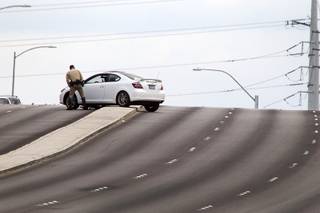 A Metro Police officer looks over a vehicle after an accident between a car and a Metro Police motorcycle officer on the Durango Drive overpass over the Summerlin Parkway Wednesday, May 8, 2013.