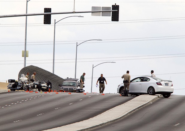 Officials investigate an accident between a car and a Metro Police motorcycle officer on the Durango Drive overpass over the Summerlin Parkway Wednesday, May 8, 2013.